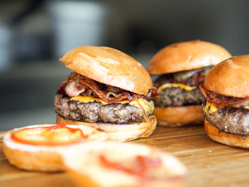 close-up of three juicy burgers on seperate buns